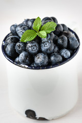 Heidelbeeren / Blaubeeren mit Minze dekoriert, in einer Tasse, frisch nach der Ernte