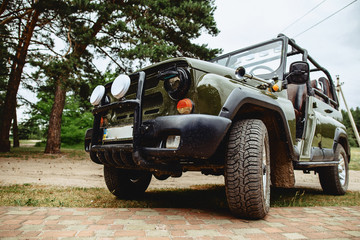 a jeep with a dark green color with aggressive rubber - obrazy, fototapety, plakaty