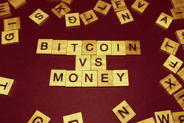 Wooden blocks on a brown background spelling words Bitcoin vs money