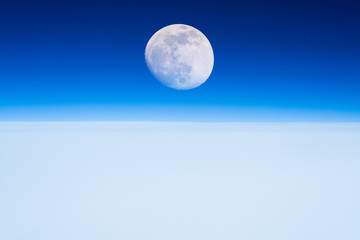Moon rising from the Earth horizon above the clouds. 