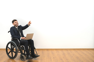 The smile disabled with a laptop gesturing on the white wall background