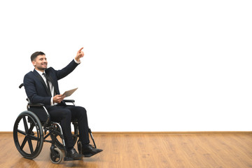The man in a wheelchair with a tablet gesturing on the white wall background