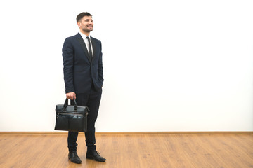 The man with a briefcase standing on the white wall background