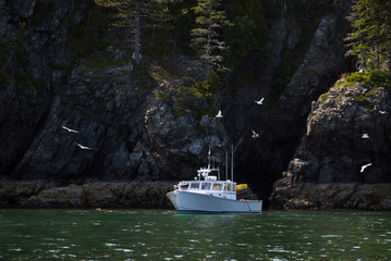 Lobster Boat Fishing by Rocky Island Cliffs in Maine