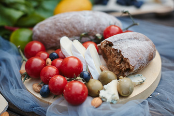 Homemade bread, cheese, cherry tomatoes, berries and nuts on a wooden salver