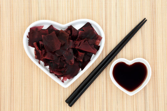 Dulse seaweed health food in a heart shaped dish with low sodium soy sauce and chopsticks on bamboo background. Super food very high in minerals and protein. 
