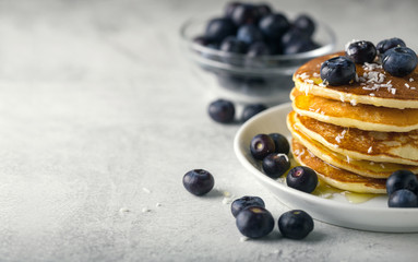 Pancakes with blueberries and honey on a plate on white background