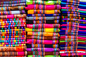 Close-up of colorful blankets stacked with Andean designs