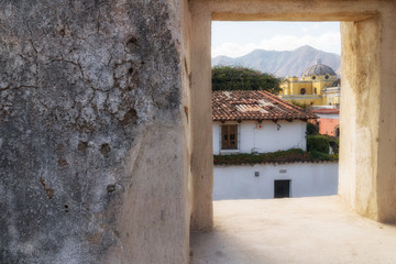 Antigua de Guatemala view to colonial houses and Iglesia La Merced through a stone window