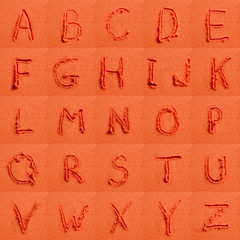 Alphabet written on orange sand