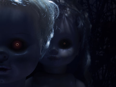 Two creepy faces of scary plastic dolls with fiery eyes, closeup.