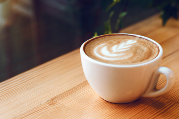 Cup of cappuccino with beautiful latte art on wooden table. Flat lay style.
