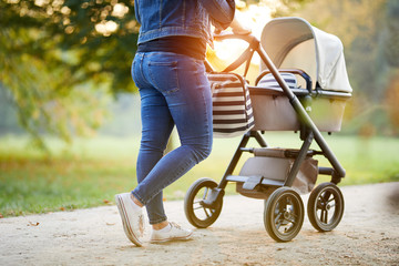 Woman with baby stroller walks in the park at sunset - 195666965