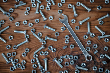 Spanner and nuts with bolts are located on a wooden surface