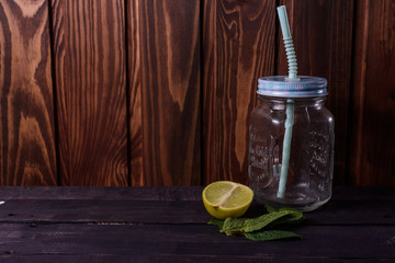 Mint and lime lie on a board near a glass cup for tea.