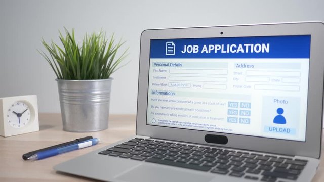 Job application form showing on a laptop computer screen sitting on a desk. Camera is slowly turning around the computer.