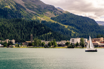Fototapeta premium Sailboat with white sails on St. Moritz lake, St. Moritz-Bad in the background