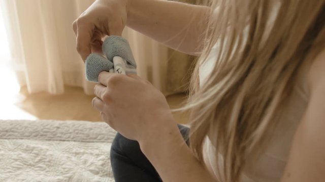 Beautiful future mother looks at tiny socks and bodysuit for her future son