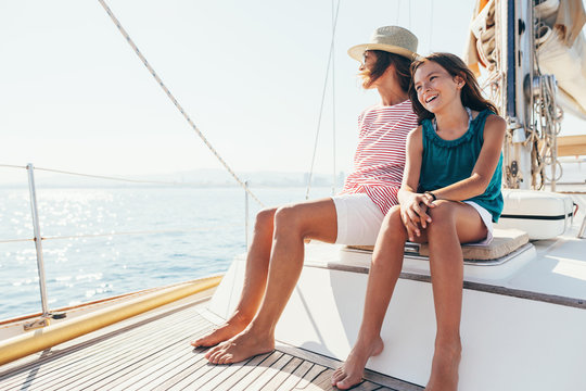 Mother and daughter enjoying a sunny day on a sailboat.