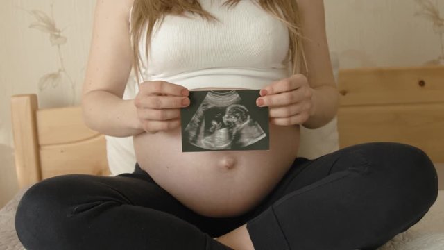 Pregnant woman showing ultrasound scans at home