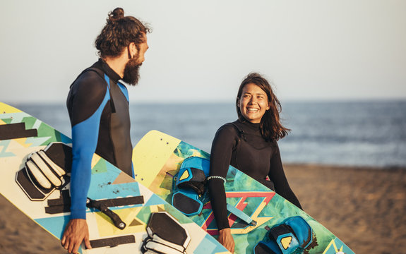 Surfers Carrying Kiteboards on the Beach