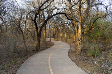 Obraz premium Concrete path and trees in the spring evening in the city park in Texas