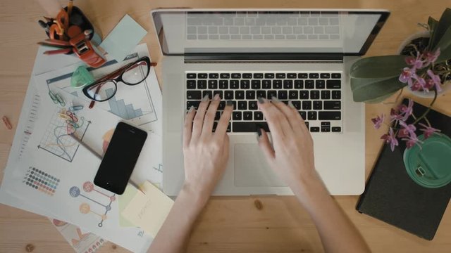 Female hands are typing on the laptop. Girl is calling from her mobile phone.