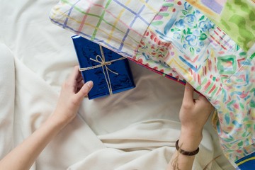 A child's hand in bed holds surprise gift.