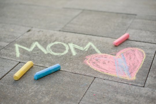 Happy Mother's Day. Child draws for her mother a picture surprise of crayons on the asphalt. LOVE MOM