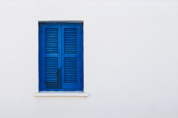 Blue window shutter on white stone house