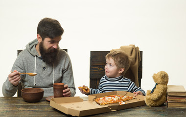 Family eating pizza together, father and boy son, happy funny child with parent. Slice of hot pizza large cheese lunch or dinner meat topping sauce with bell pepper, vegetables delicious. Happy family