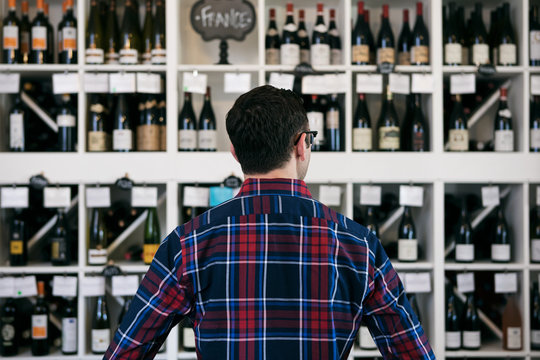 Wine: Man Overwhelmed In Front Of Wall Of Wine Choices