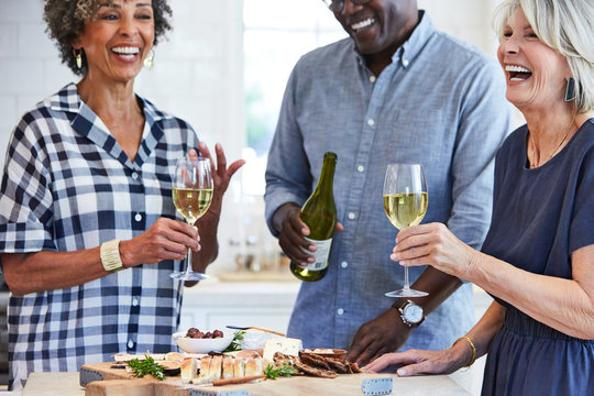 Senior friends enjoying wine and cheese in the kitchen