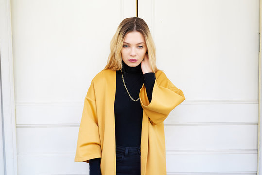 Attractive blonde girl in black and yellow with hand on neck ove