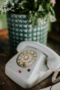 Old white rotary telephone on a table