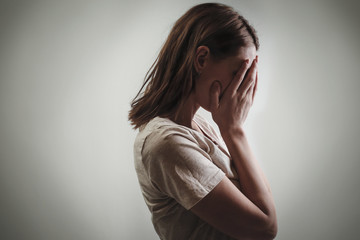 Fototapeta premium Portrait of depressed woman, covering face with her hands, side view