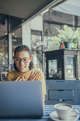 Happiness Asian woman sitting using laptop in a cafe.
Focus on face
