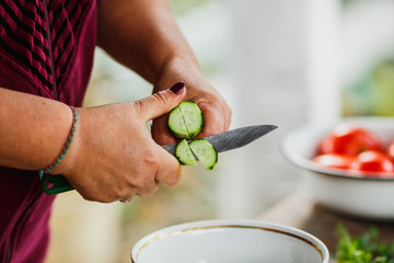 the cooking process for fresh vegetable salad,  healthy nutrition, women's hands cut cucumbers and tomatoes