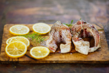 the process of cooking fish, two fresh raw tasty pieces of fish with lemon slices and parsley on wooden Board