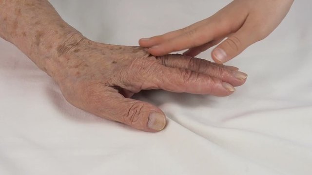 The child strokes the old hands. Children's hands embrace the hands of an elderly person.