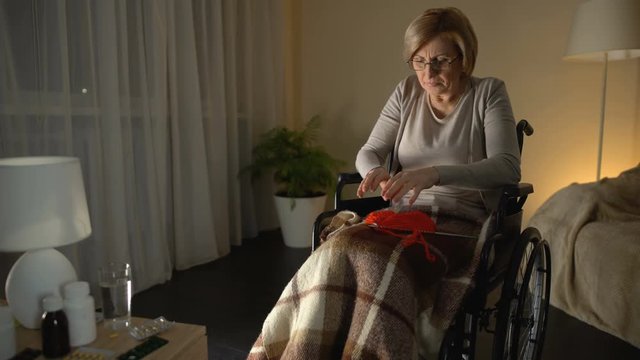 Woman in wheelchair suffering from parkinsonian tremor, helplessness in old age