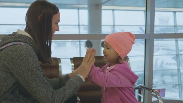 Yound mother and little cute daughter having fun at airport in slow motion.