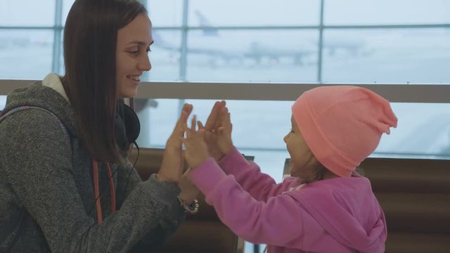 Yound mother and little cute daughter having fun at airport in slow motion.