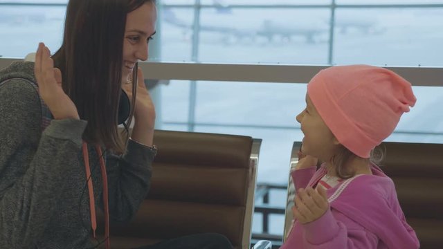 Yound mother and little cute daughter having fun at airport in slow motion.