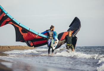 Kitesurfers Carrying Kites and Boards on the Beach