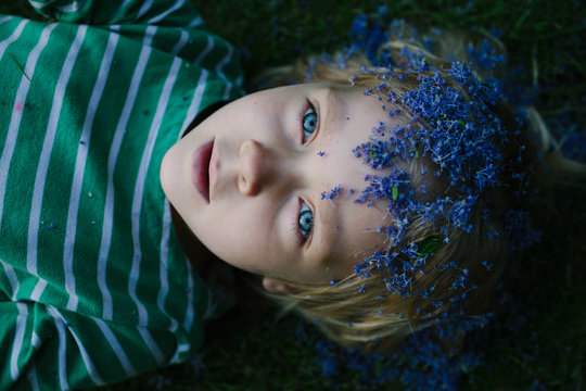 Little girl with Lilac petals on her head plays at dusk.
