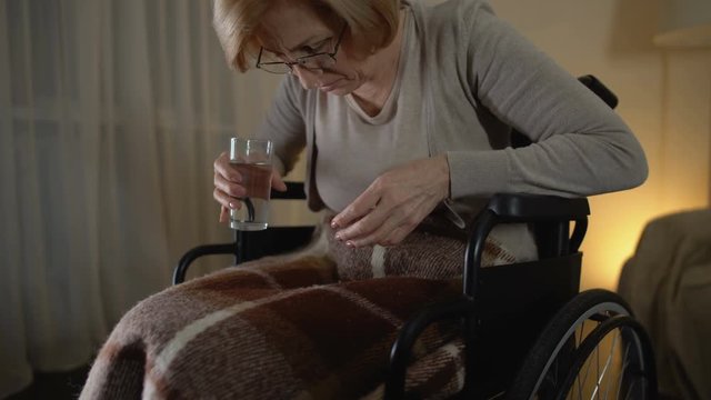 Female patient suffering alzheimers disease, trying to take medicine, desperate
