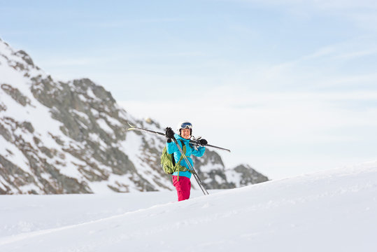 Female skier carrying her equipment on snowy mountain plateau