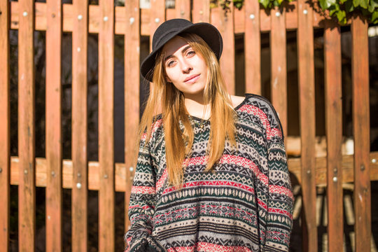 Beautiful young woman looking at camera in front of the wooden f