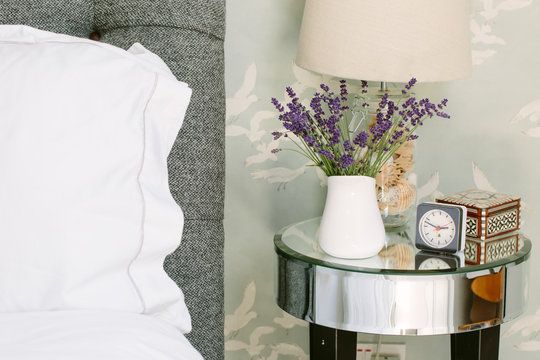 A jug of lavender next to a bed.